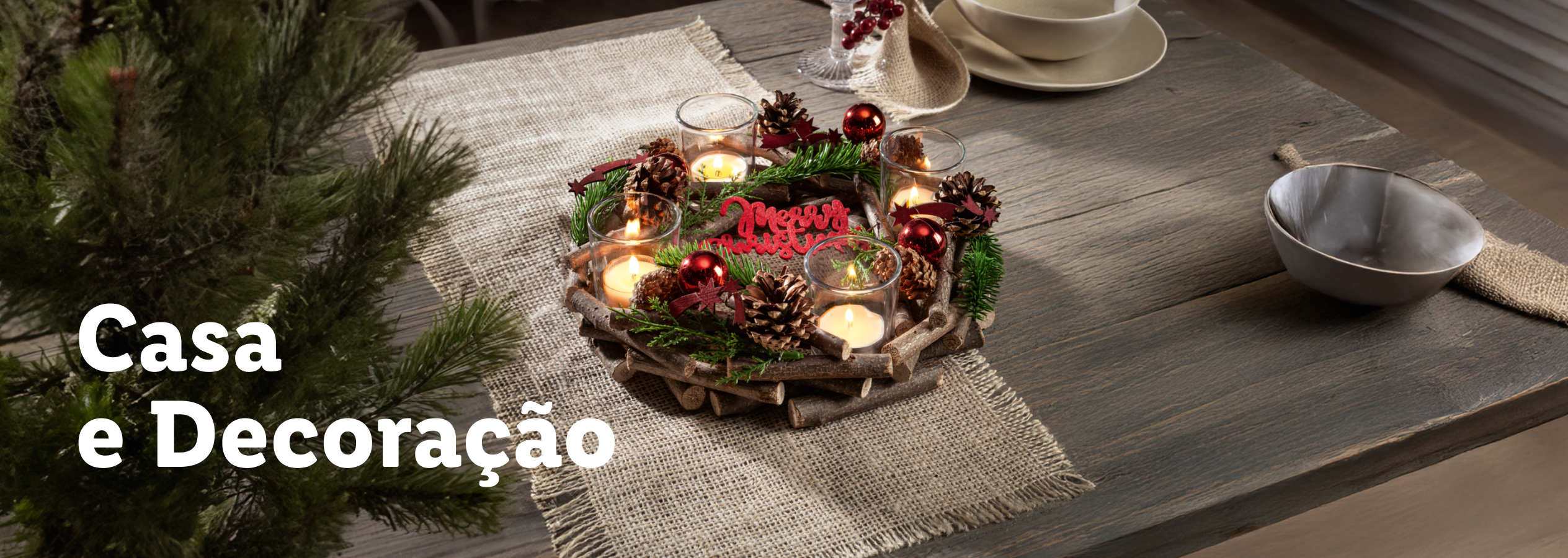 Decoração de Natal com velas, pinhas e ramos, sobre uma mesa de madeira rústica.