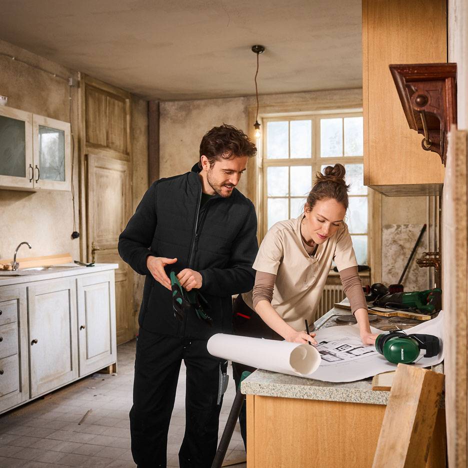 Homem e mulher com roupa de trabalho a planear a renovação de uma cozinha.