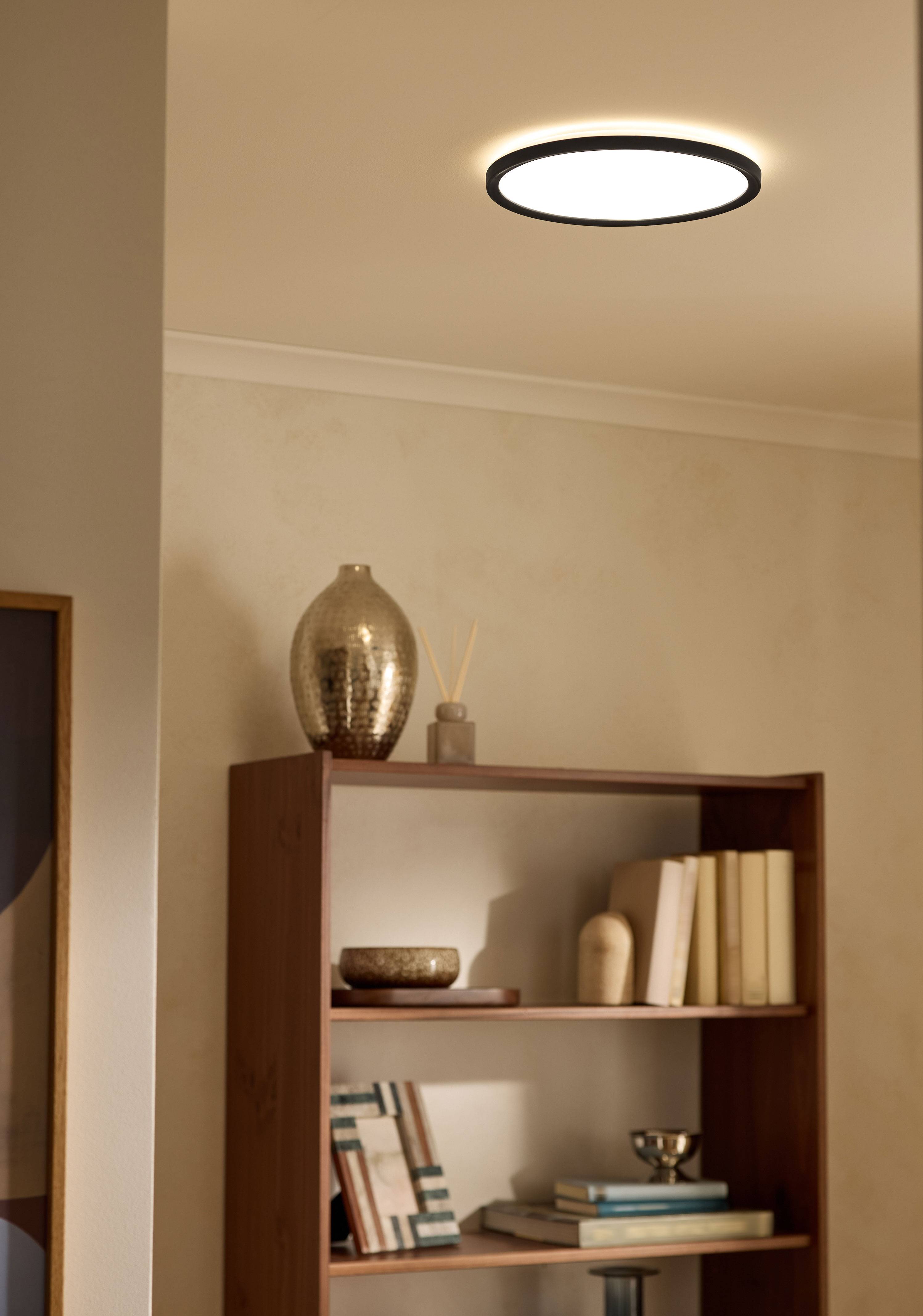 Candeeiro de teto ilumina uma estante de sala de estar com livros e decoração.