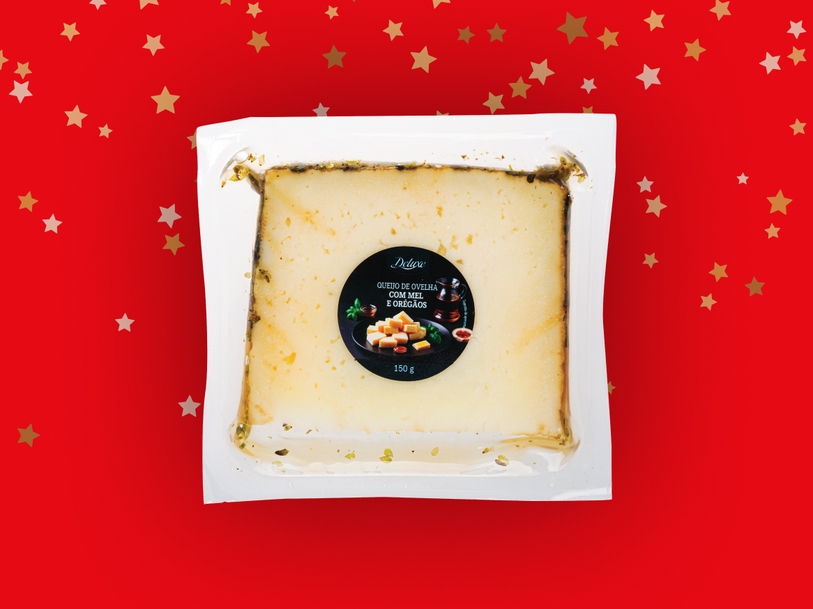 Queijo de ovelha Deluxe com mel e orégãos, embalado a vácuo, sobre fundo vermelho com estrelas.
