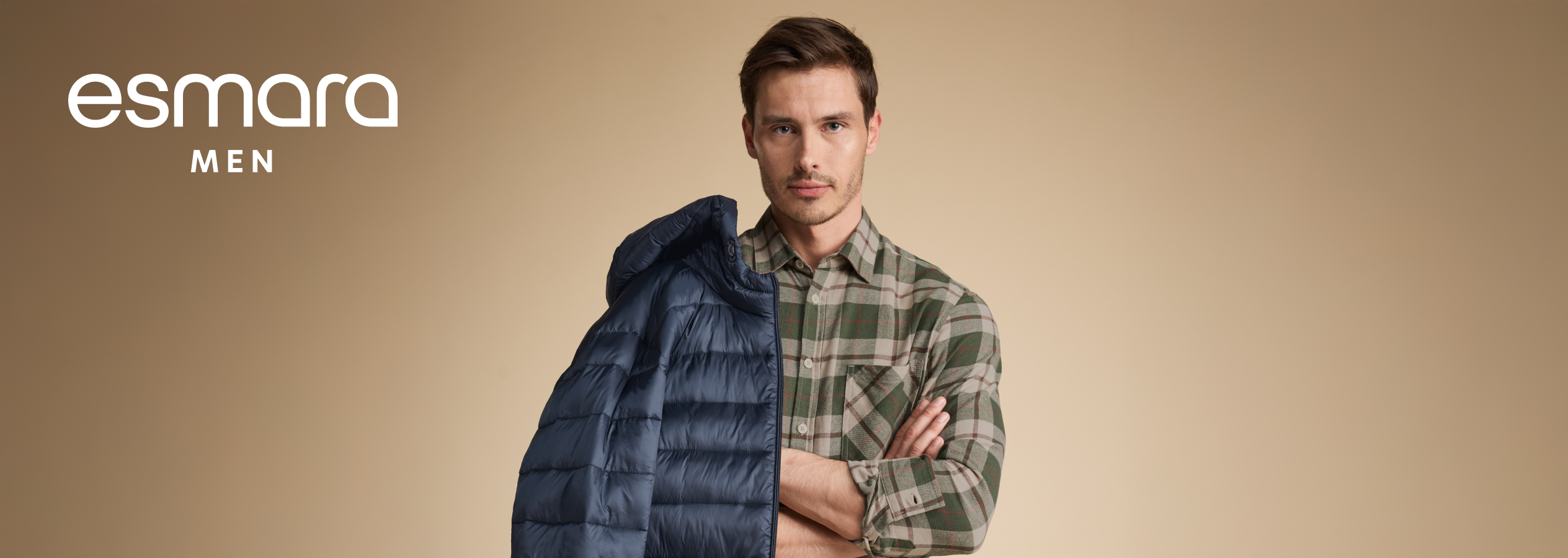 Um homem com uma camisa xadrez verde e um casaco azul acolchoado, com o logótipo Esmara Men.