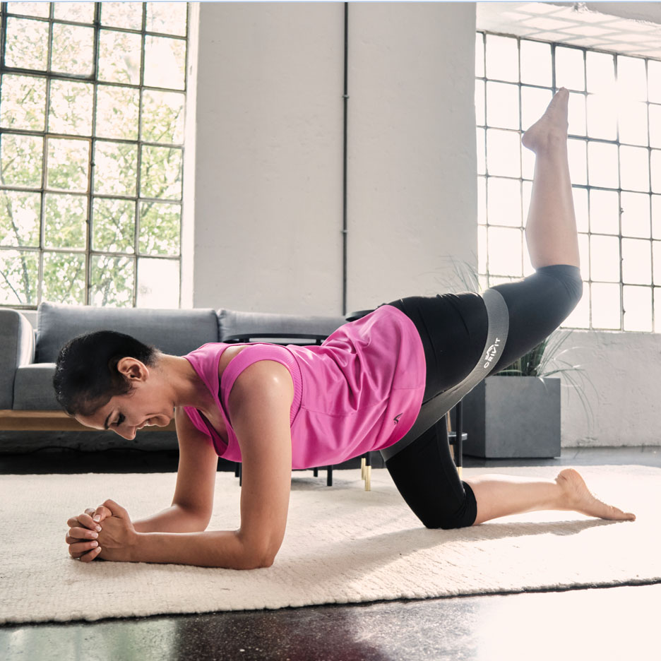 Mulher fazendo exercícios de pernas com faixa de resistência Senfit.