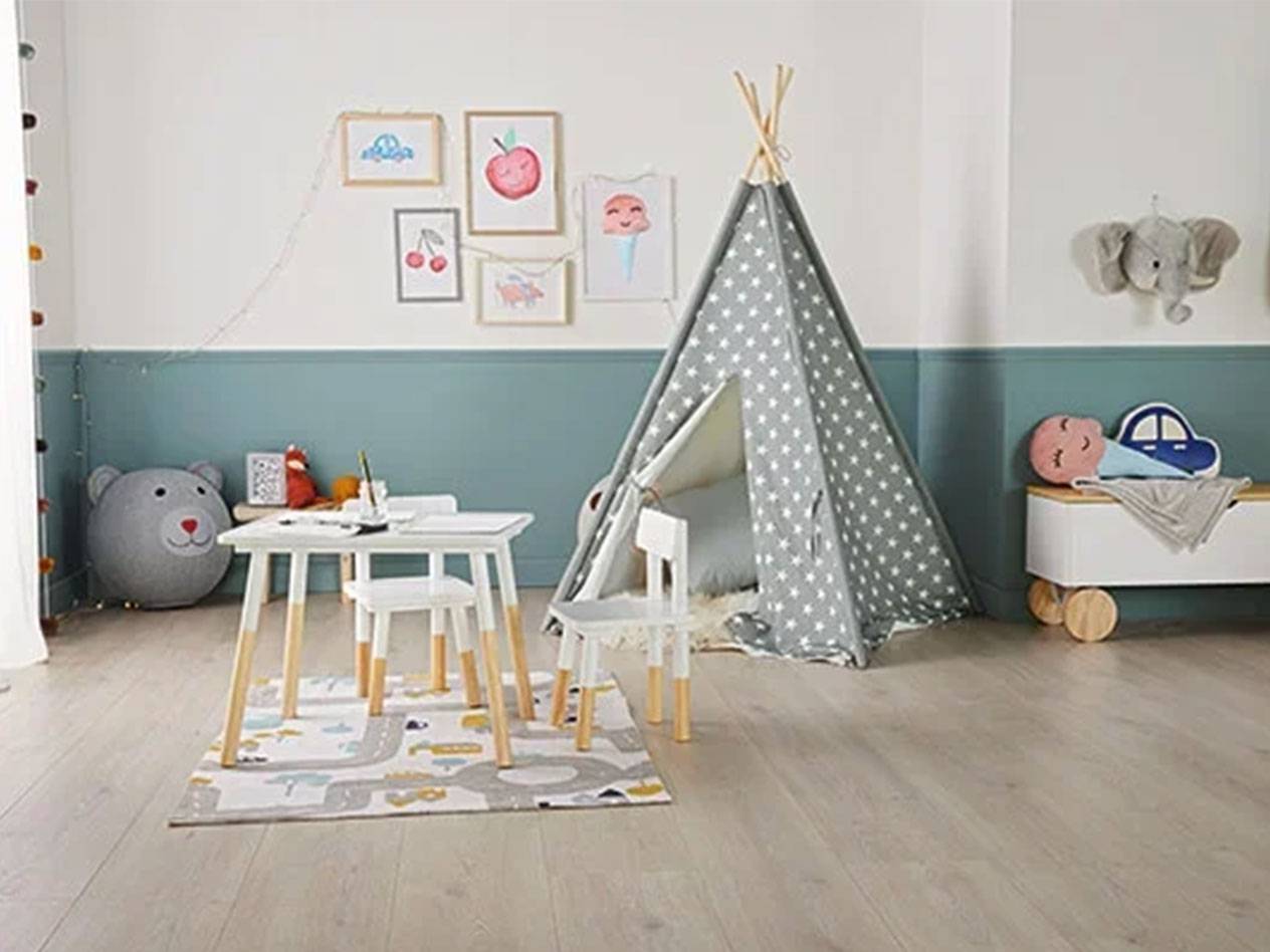 Quarto infantil com tenda tipi, mesa e cadeiras, baú de brinquedos e quadros na parede.