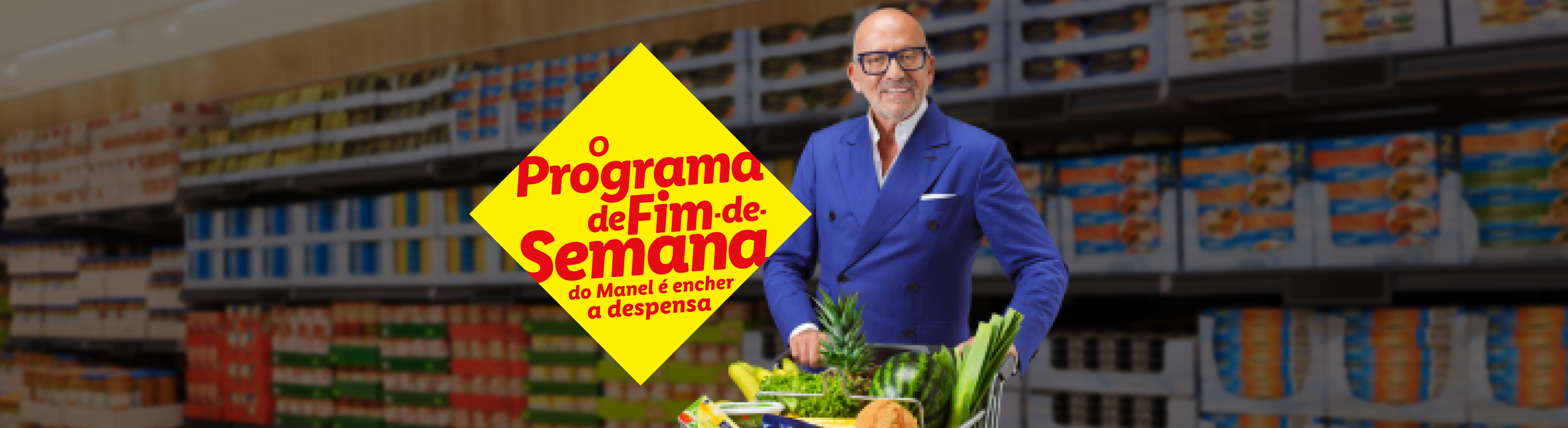 Um homem sorridente empurra um carrinho de compras cheio de frutas e vegetais em um supermercado.