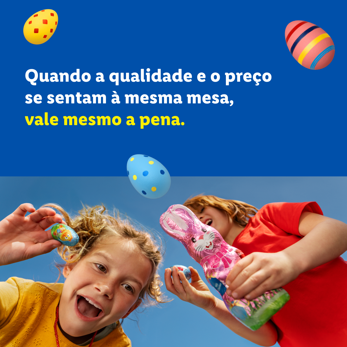 Duas crianças felizes com ovos de Páscoa e um coelho de chocolate, com o texto: 'Quando a qualidade e o preço se sentam à mesma mesa, vale mesmo a pena.'