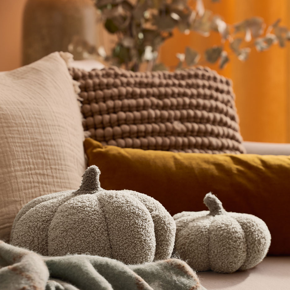 Sofá aconchegante com almofadas decorativas e duas almofadas macias em forma de abóbora.