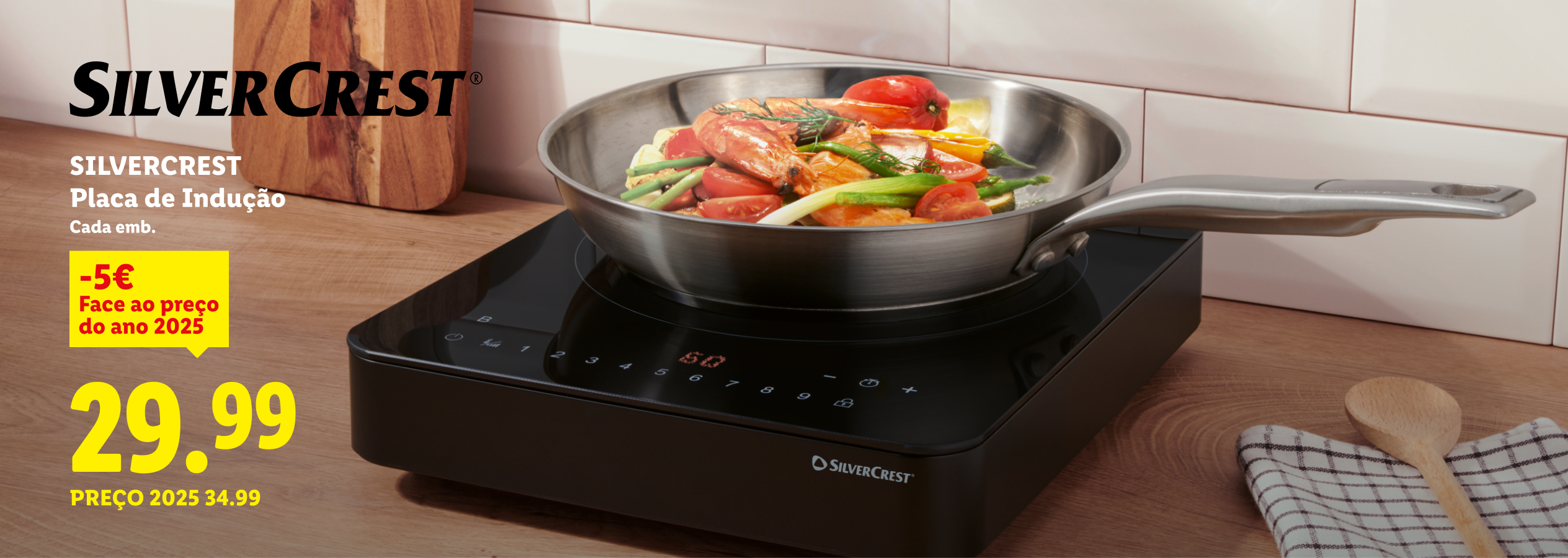 Placa de indução com uma frigideira cheia de legumes e camarão, com o preço de 29,99€.