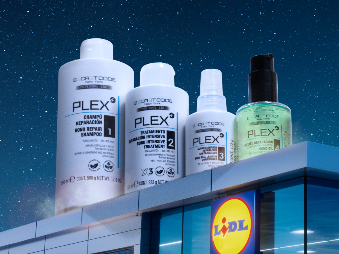 Quatro produtos de cuidado capilar, incluindo champô, tratamento intensivo, condicionador sem enxaguamento e óleo, em cima de um edifício Lidl.