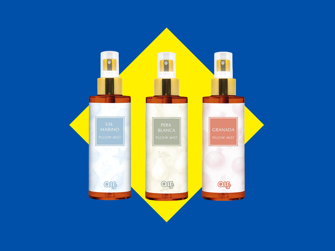 Três sprays de almofada com rótulos de Sal Marinho, Pera Branca e Granada, sobre um fundo azul e amarelo.