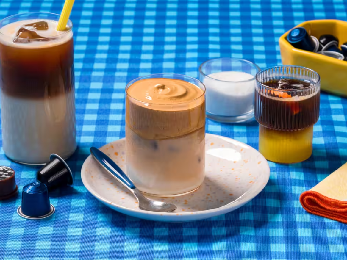 Bebidas de café geladas, incluindo café com leite e café Dalgona, em cima de uma toalha de mesa azul xadrez.