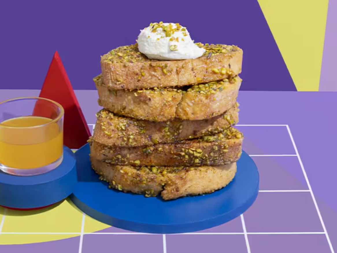 Torradas francesas com pistácios e chantilly, sumo de laranja e fundo abstrato.