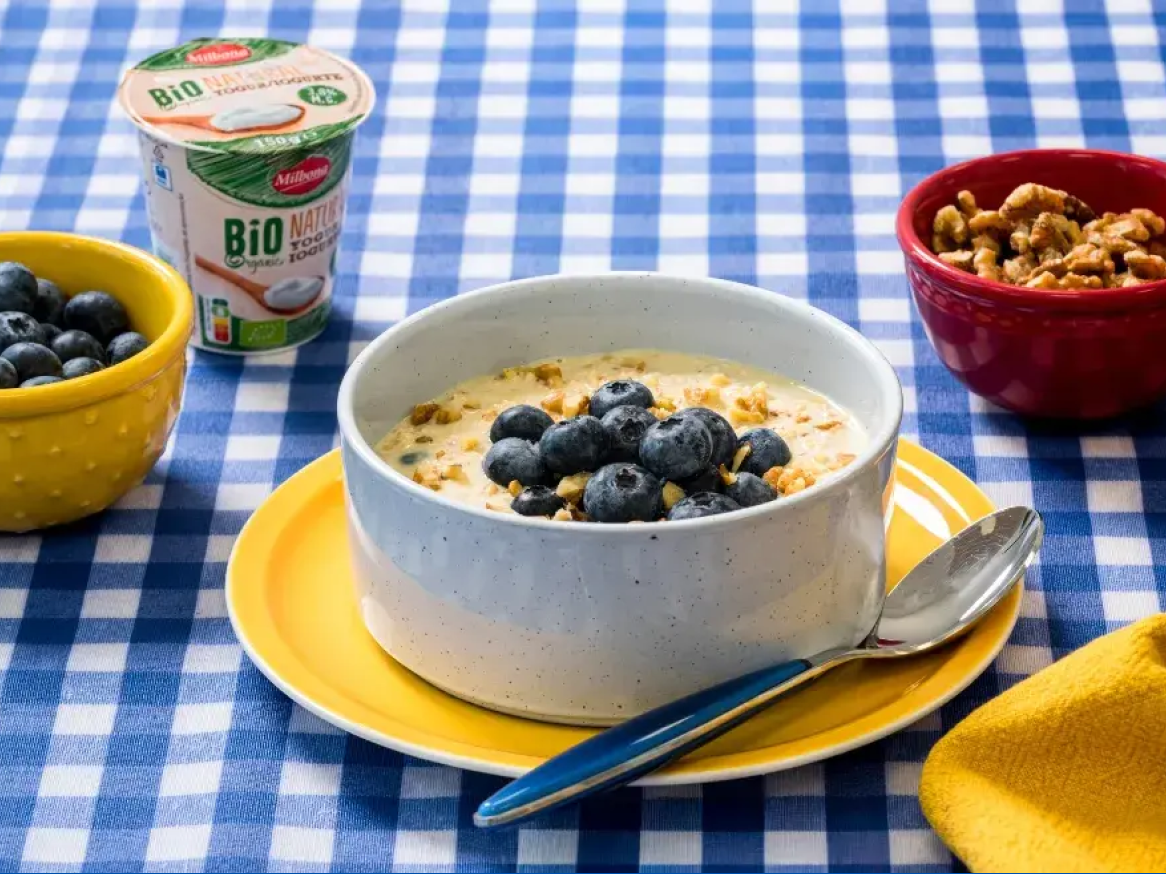 Pequeno-almoço com iogurte, mirtilos e nozes numa toalha de mesa xadrez azul e branca.