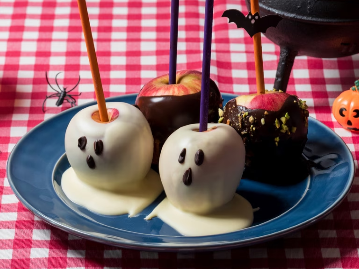 Maçãs caramelizadas com cobertura de chocolate e decorações de Halloween.