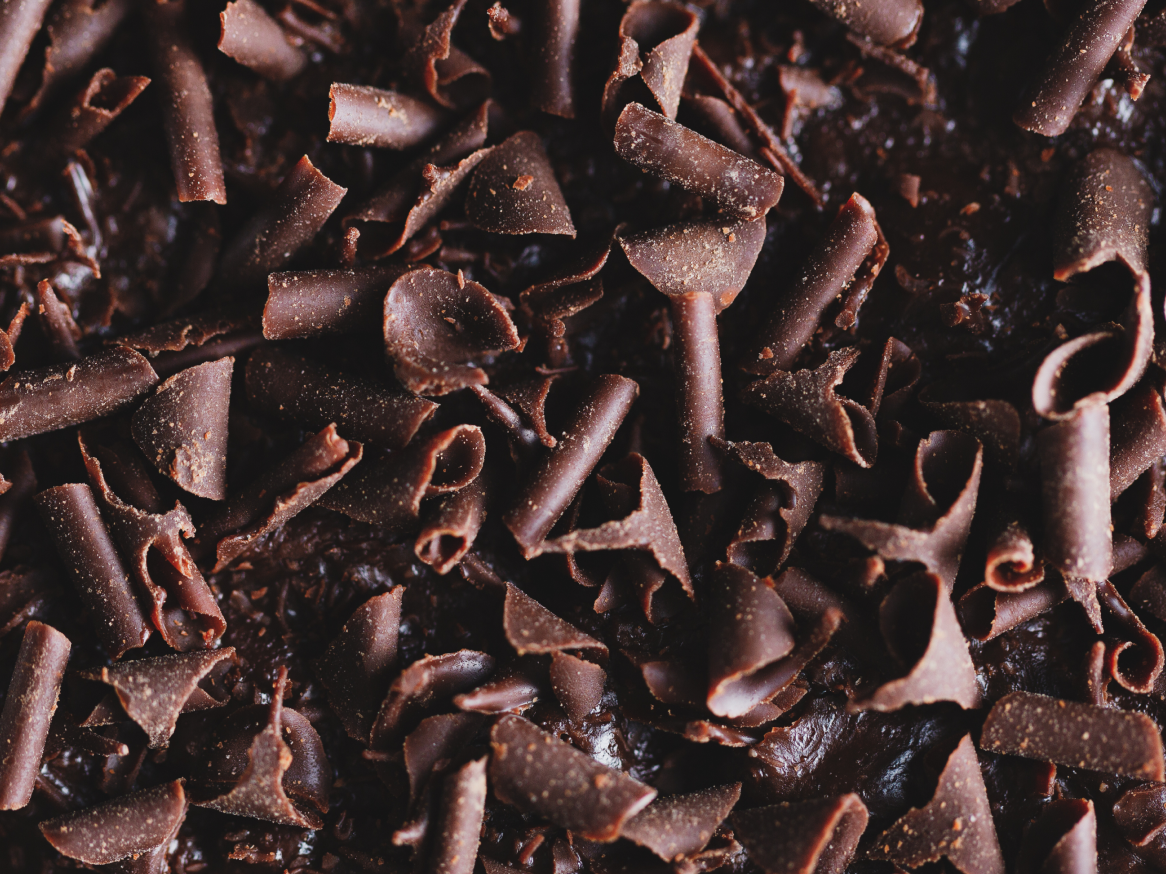 Raspas de chocolate escuro sobre uma superfície de chocolate cremoso.