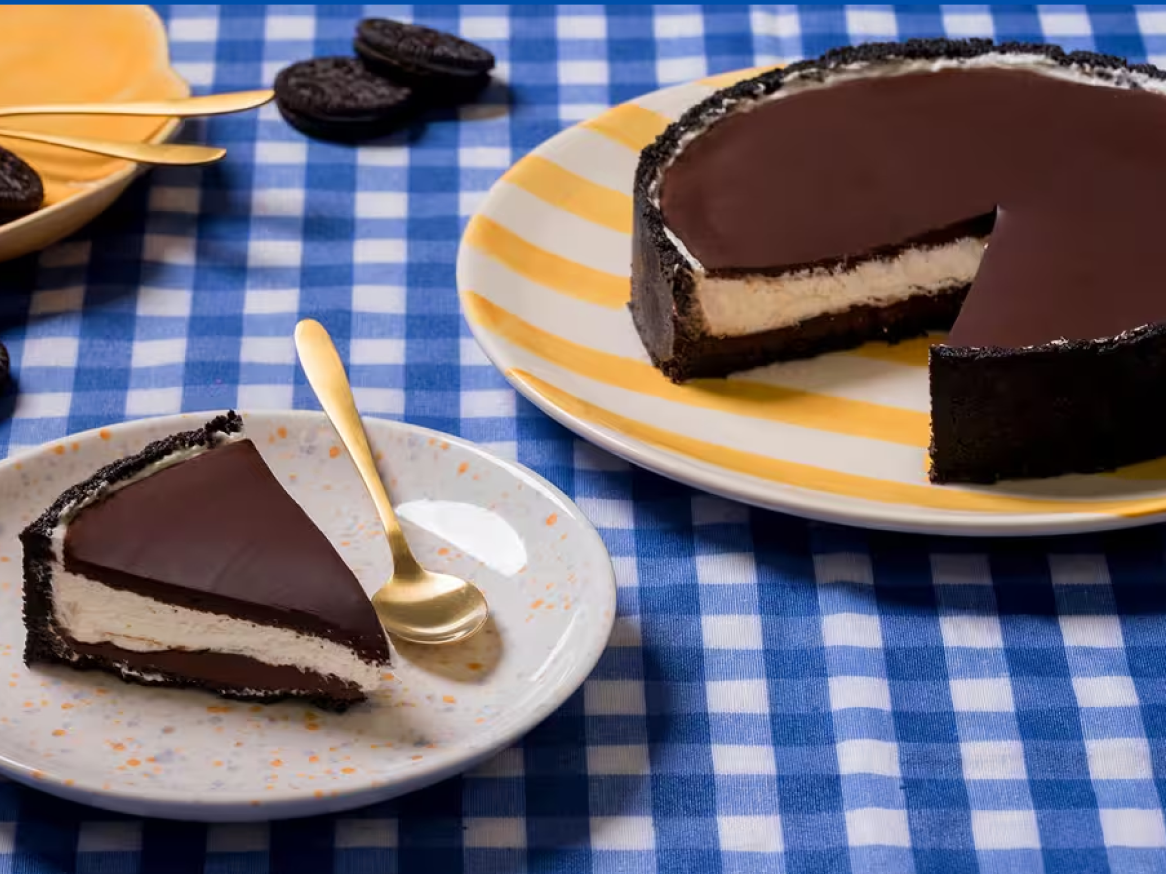 Cheesecake de chocolate com base de bolacha e recheio cremoso, servido numa toalha axadrezada.