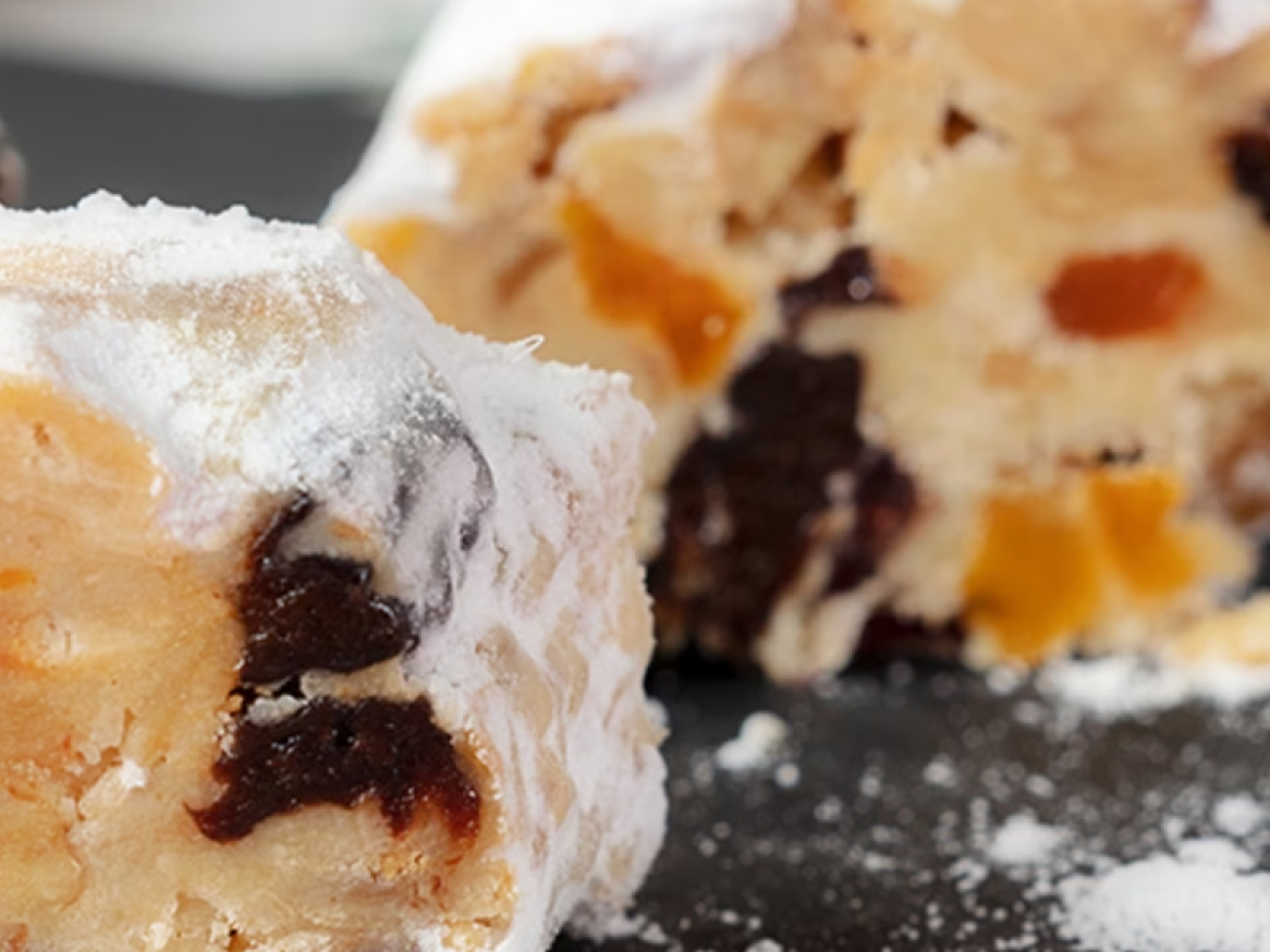 Fatias de stollen de Natal polvilhadas com açúcar em pó, com frutos secos visíveis.