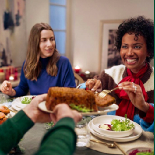 Pessoas a desfrutar de uma refeição festiva com um bolo de carne ou pão de carne.