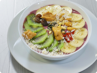 Taça de açaí com banana, kiwi, manteiga de amendoim, sementes e coco ralado.