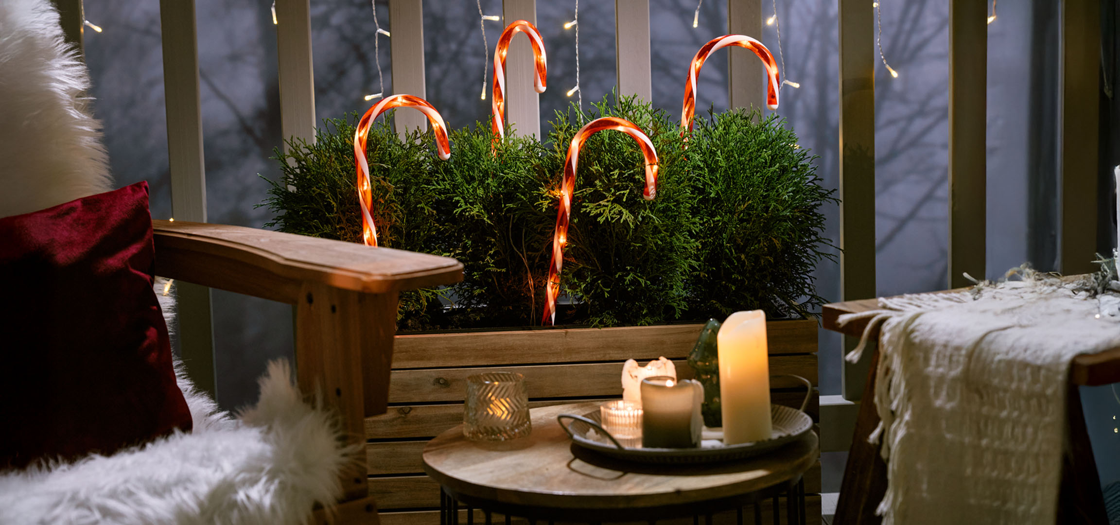 Varanda decorada para o Natal com uma cadeira, velas e bengalas doces.