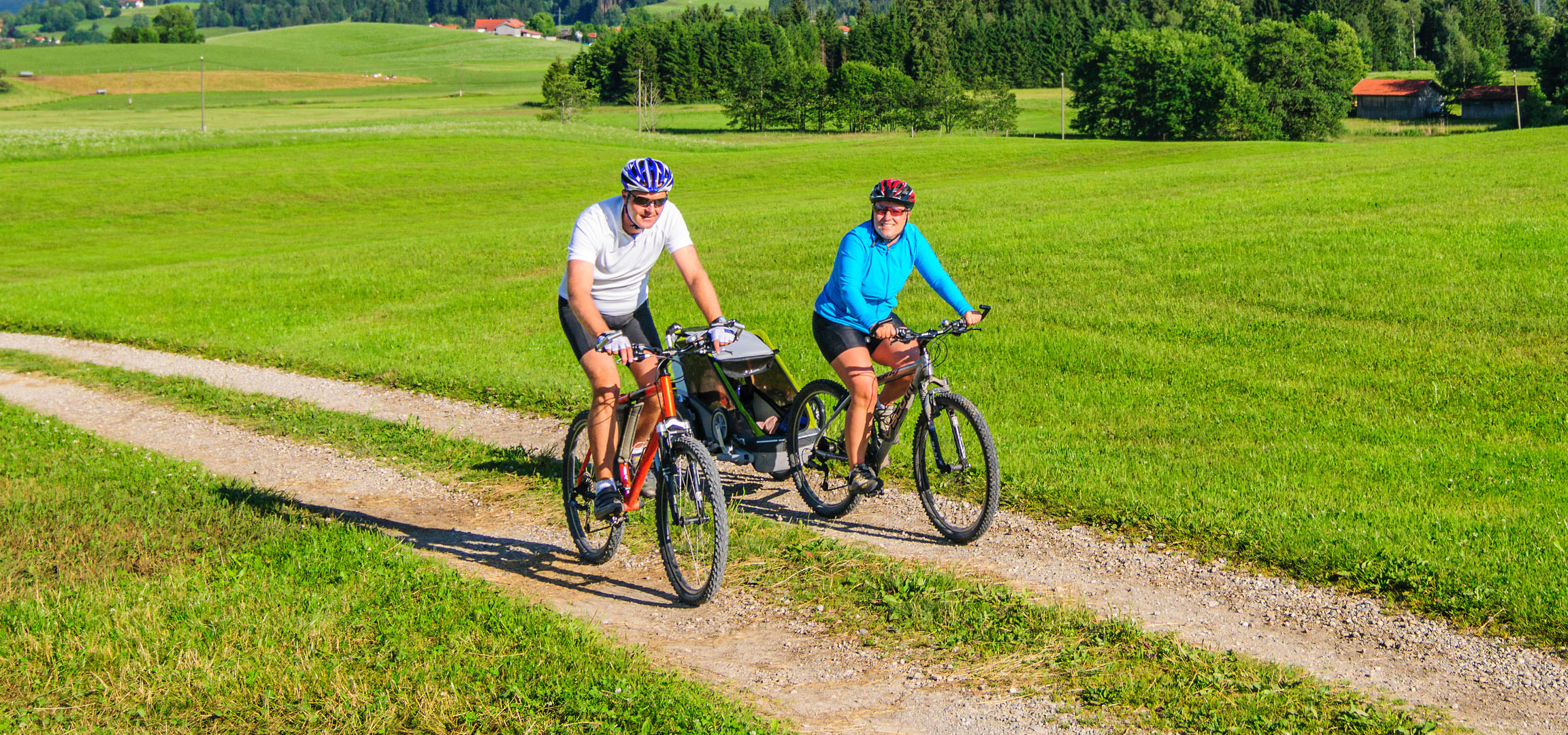 Casal andando de bicicleta em uma paisagem verde.