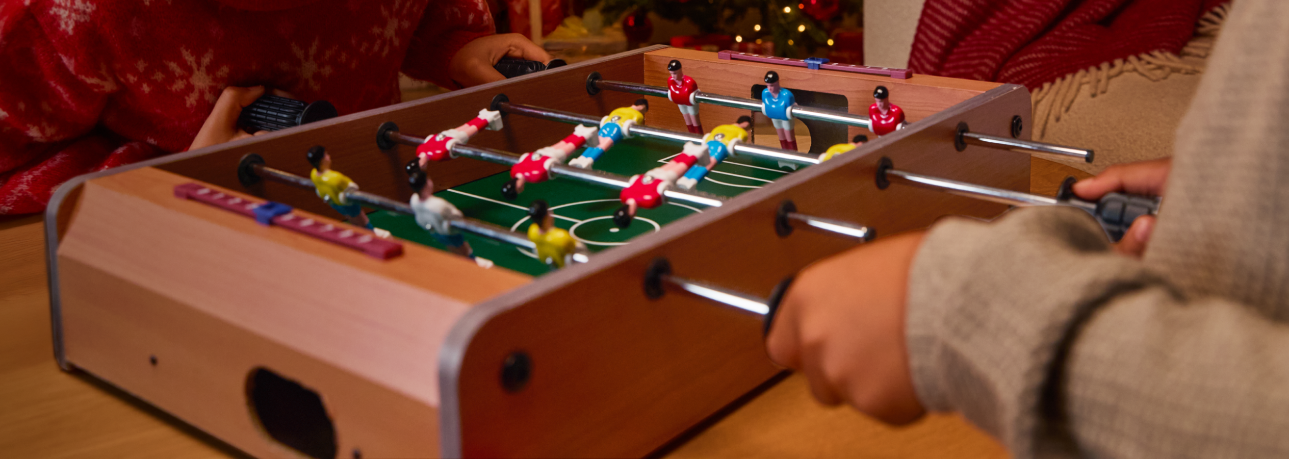 Duas pessoas a jogar matraquilhos, com um fundo festivo de Natal.