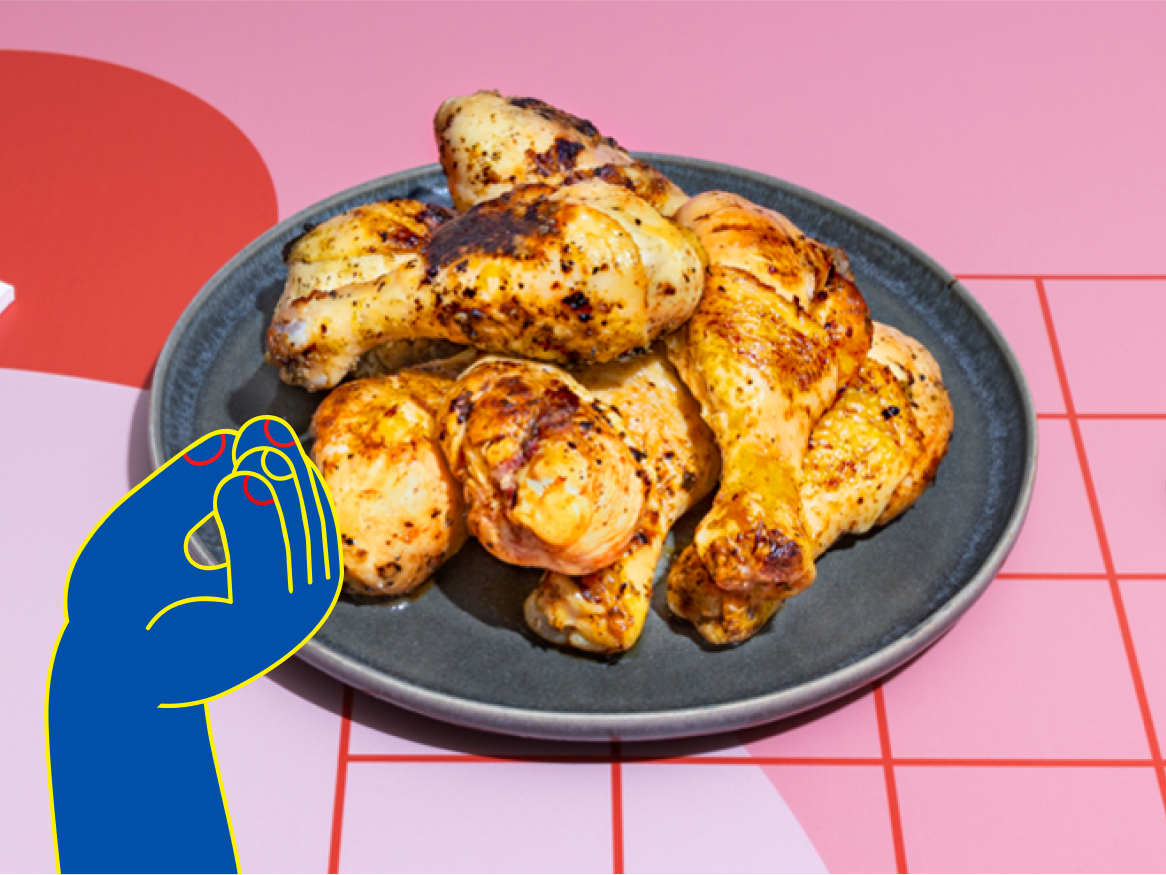 Pernas de frango assadas em um prato cinza sobre uma superfície rosa.