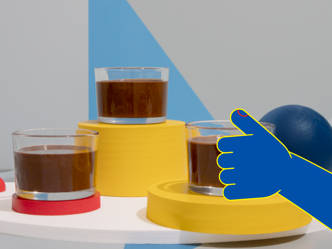 Três copos de mousse de chocolate em plataformas coloridas, com uma mão azul estilizada indicando um deles.