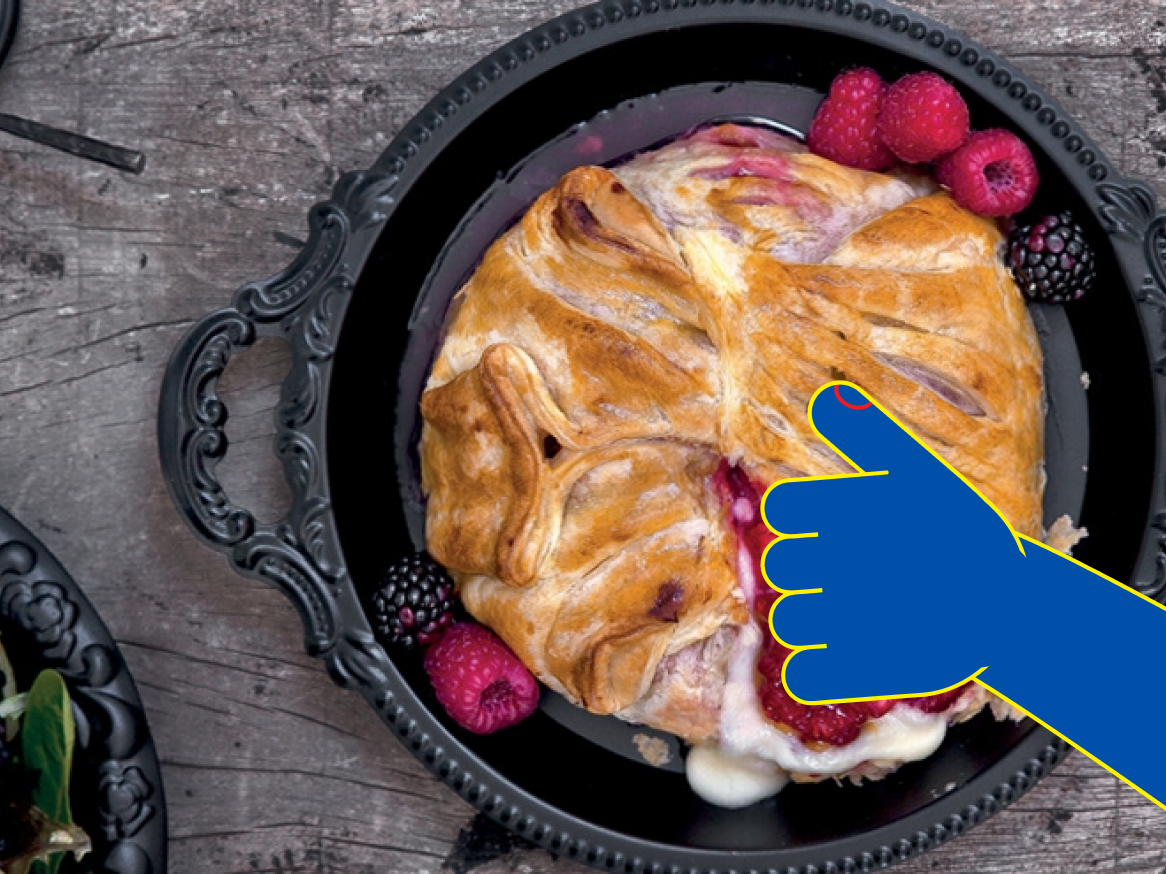 Um delicioso brie assado com frutas vermelhas, servido em uma bandeja preta elegante.