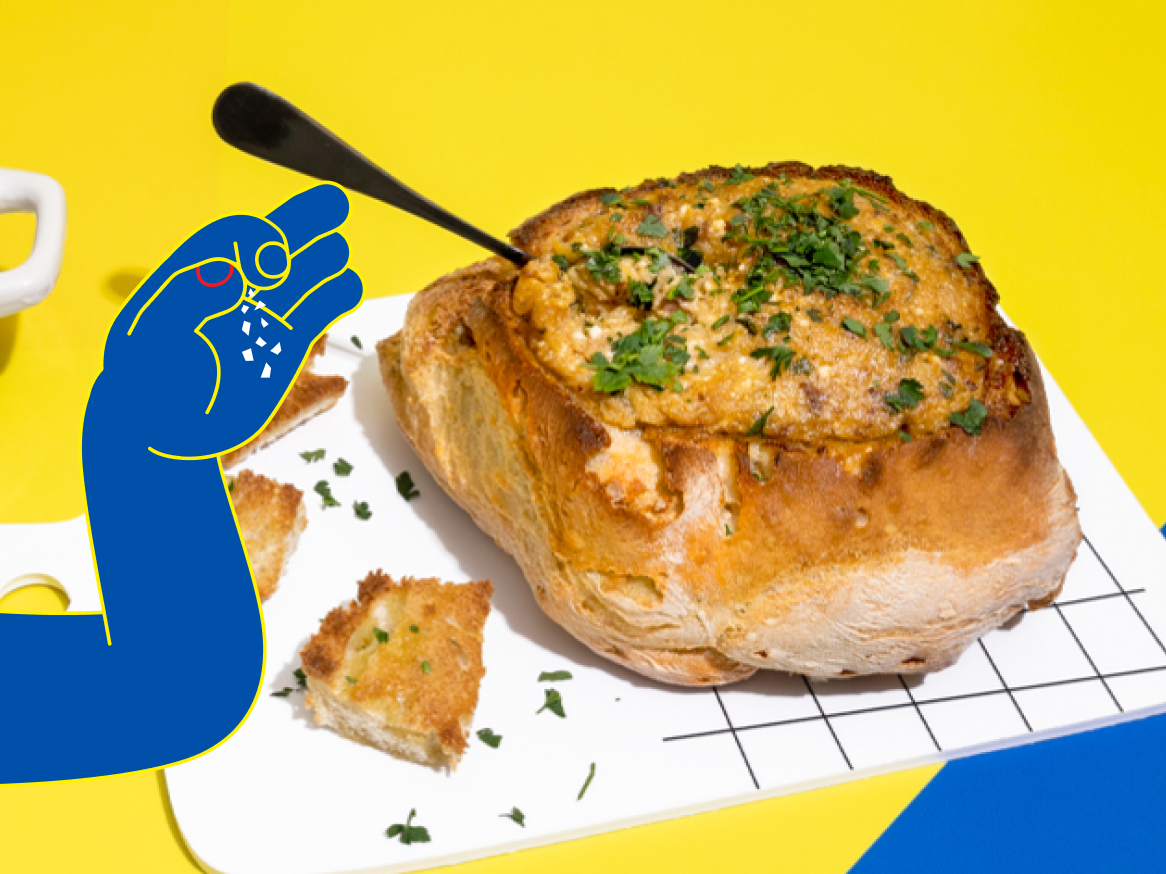 Um pão recheado com um delicioso patê, coberto com salsa e sendo temperado com sal.