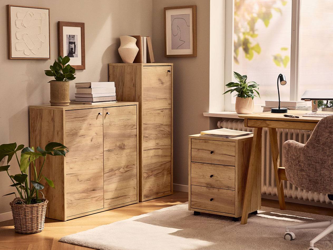 Um escritório em casa com armários de madeira clara, uma cadeira de escritório e um candeeiro de secretária.