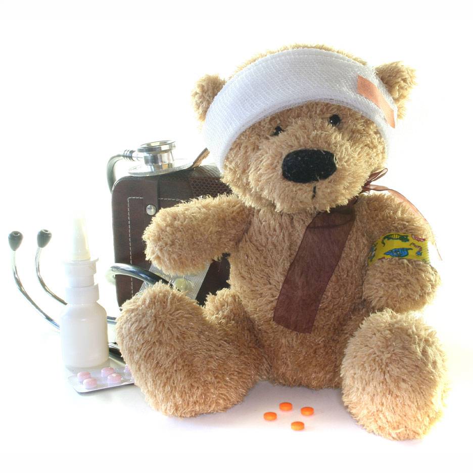 Urso de peluche ferido com ligadura na cabeça, mala médica, estetoscópio e medicamentos.