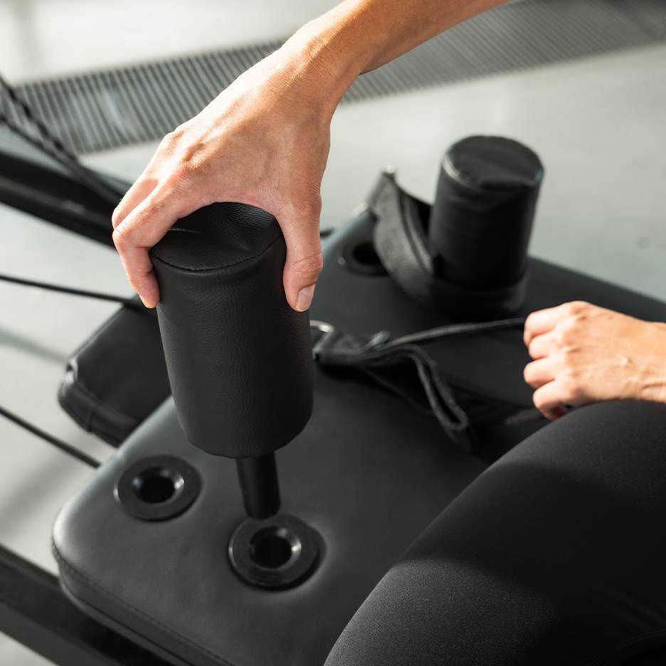 Pessoa a ajustar uma máquina de exercício almofadada preta.