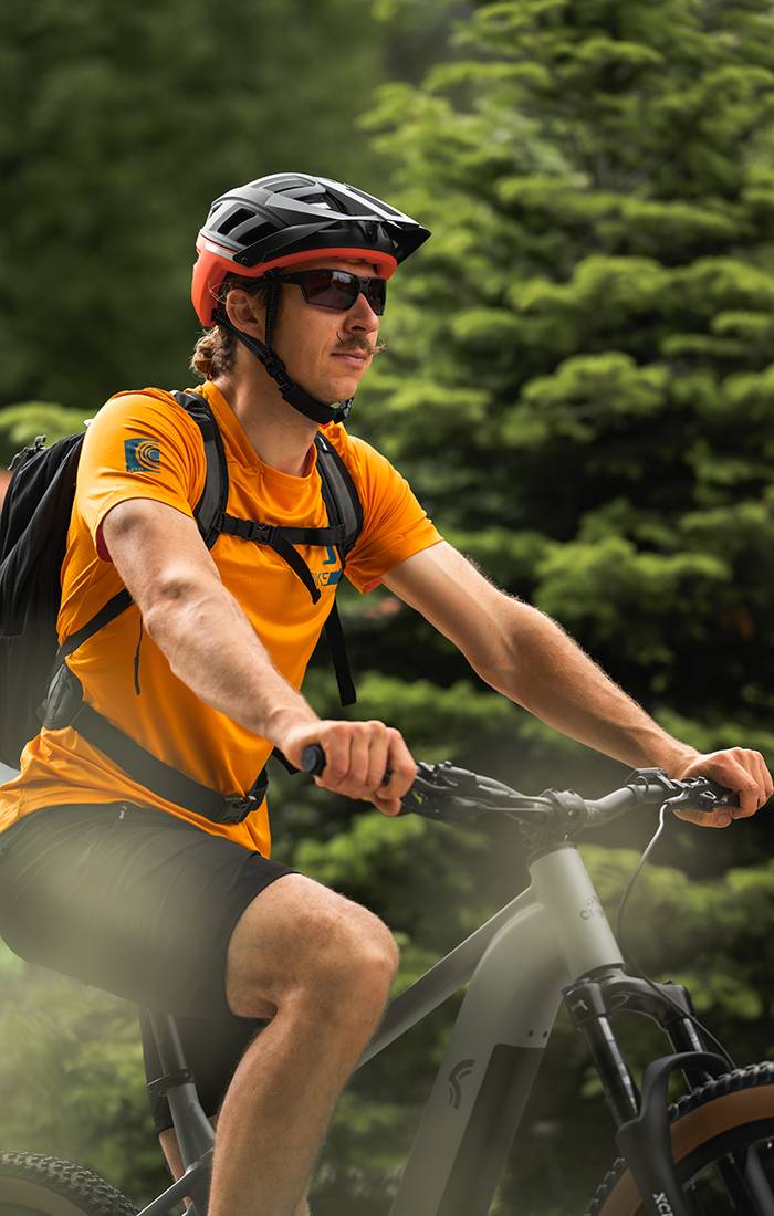 Homem andando de bicicleta de montanha usando capacete e roupa esportiva.
