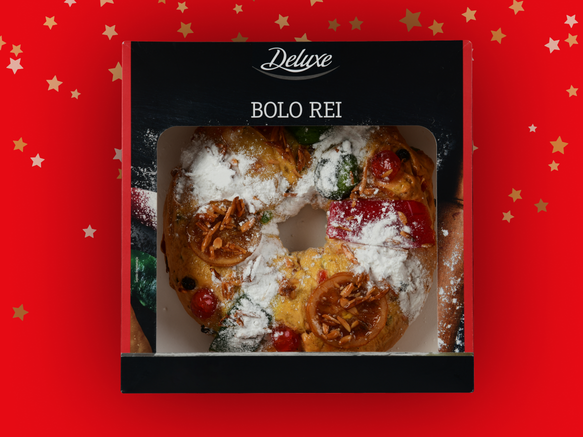 Bolo Rei Deluxe em caixa preta, com fundo vermelho e estrelas douradas.