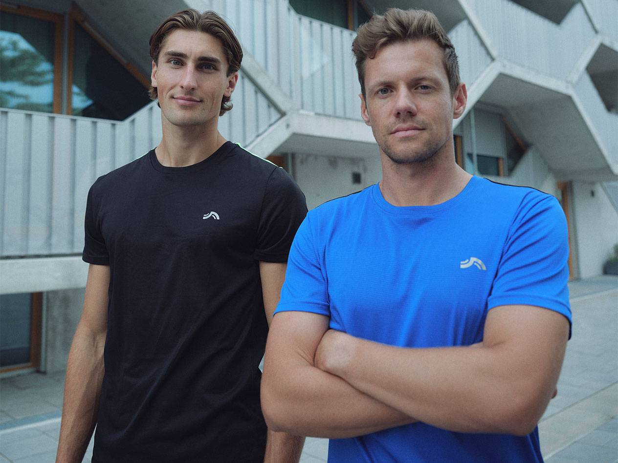 Dois homens em t-shirts desportivas pretas e azuis com logótipo.