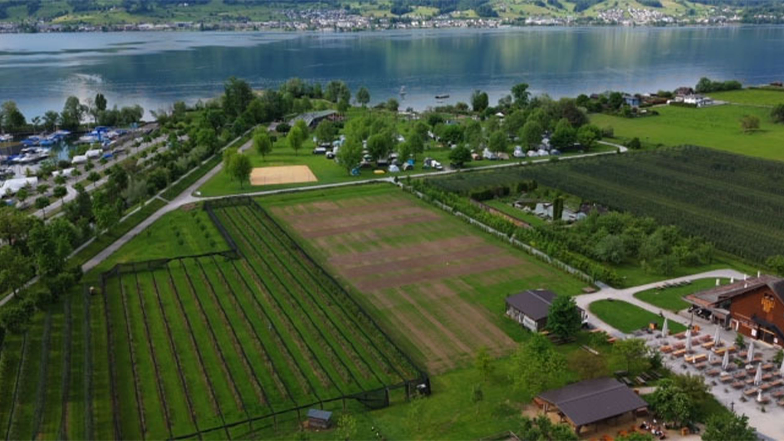 Vista aérea de um camping perto de um lago, com jardins e um restaurante.