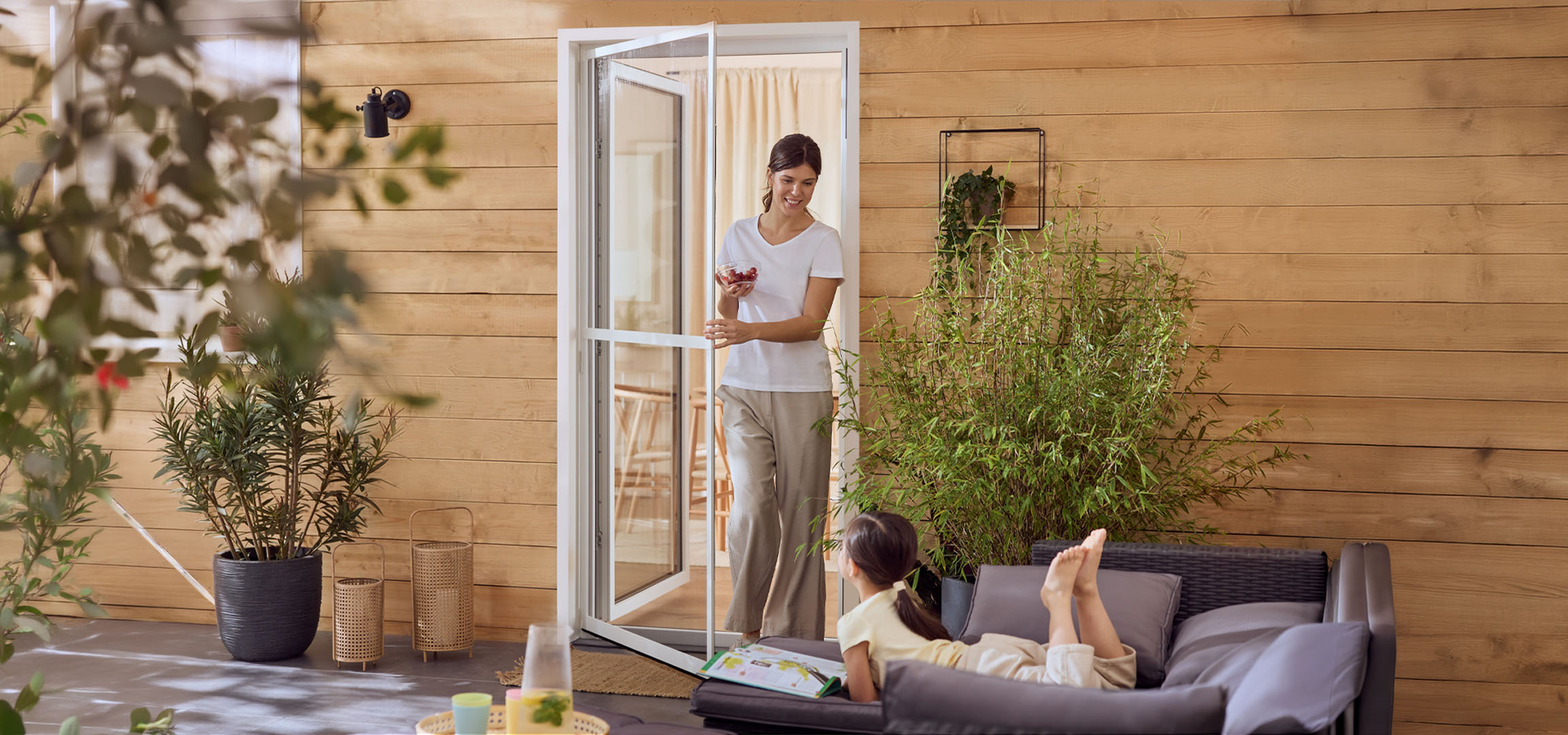 Mulher e menina desfrutando de um pátio com móveis de exterior e plantas.