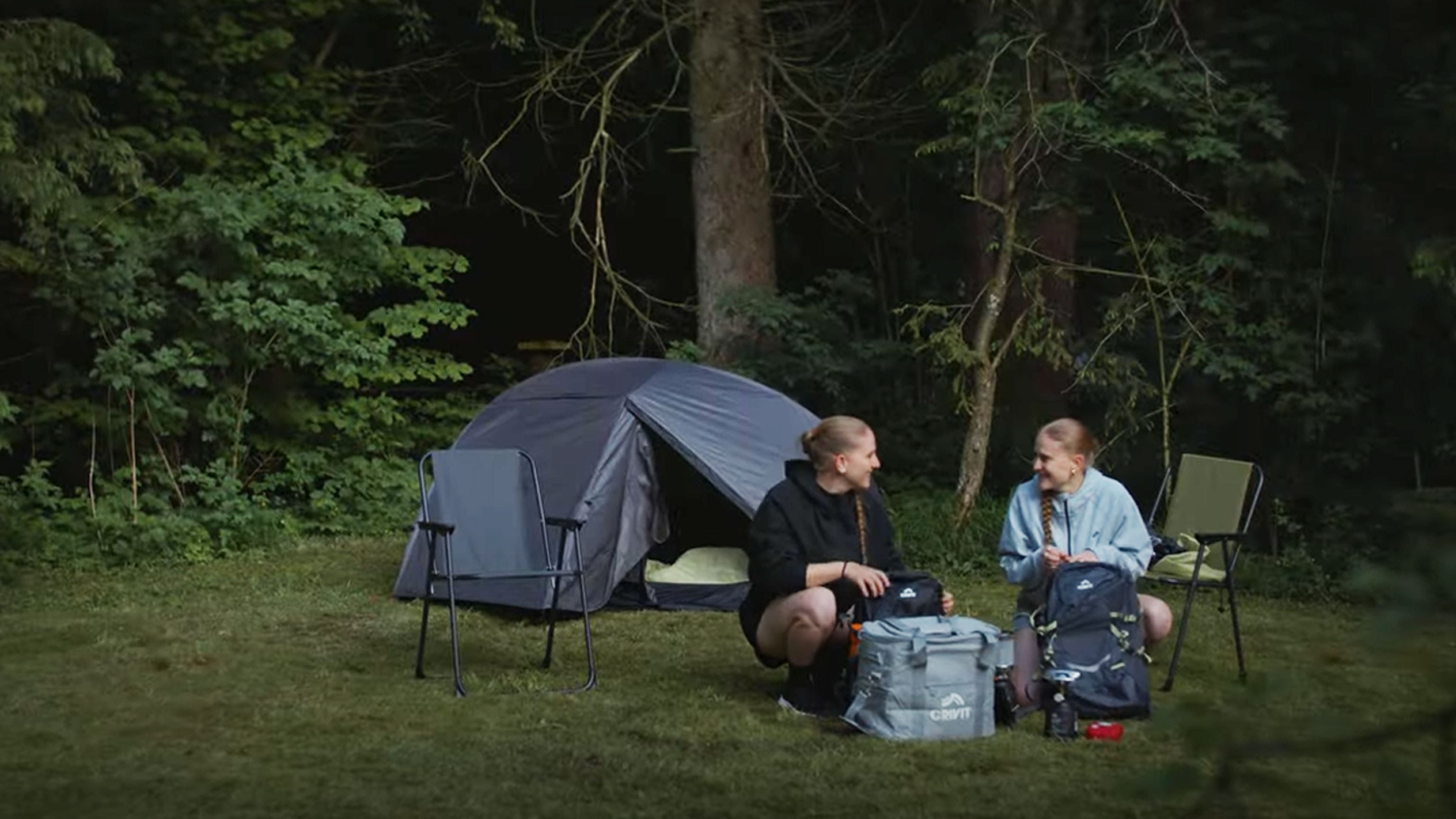Duas mulheres acampando com uma barraca Crivit e cadeiras dobráveis.