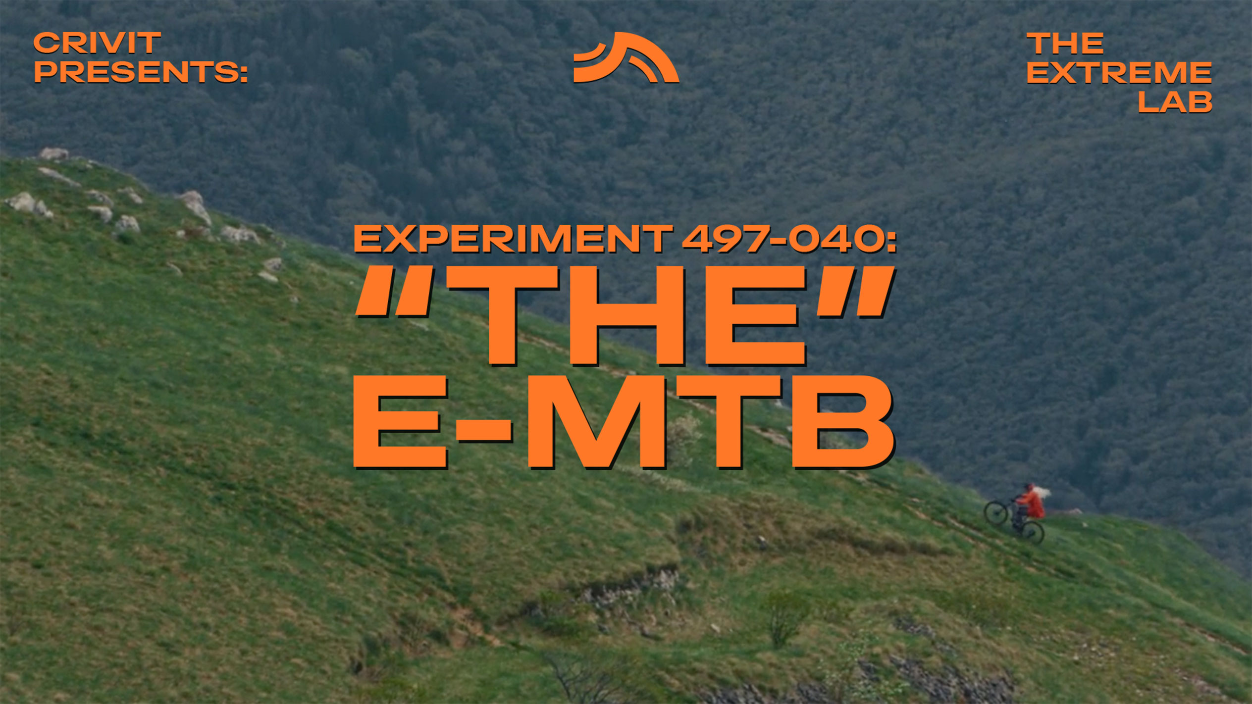 Ciclista de montanha numa encosta relvada, com texto 'THE E-MTB' e 'THE EXTREME LAB'.