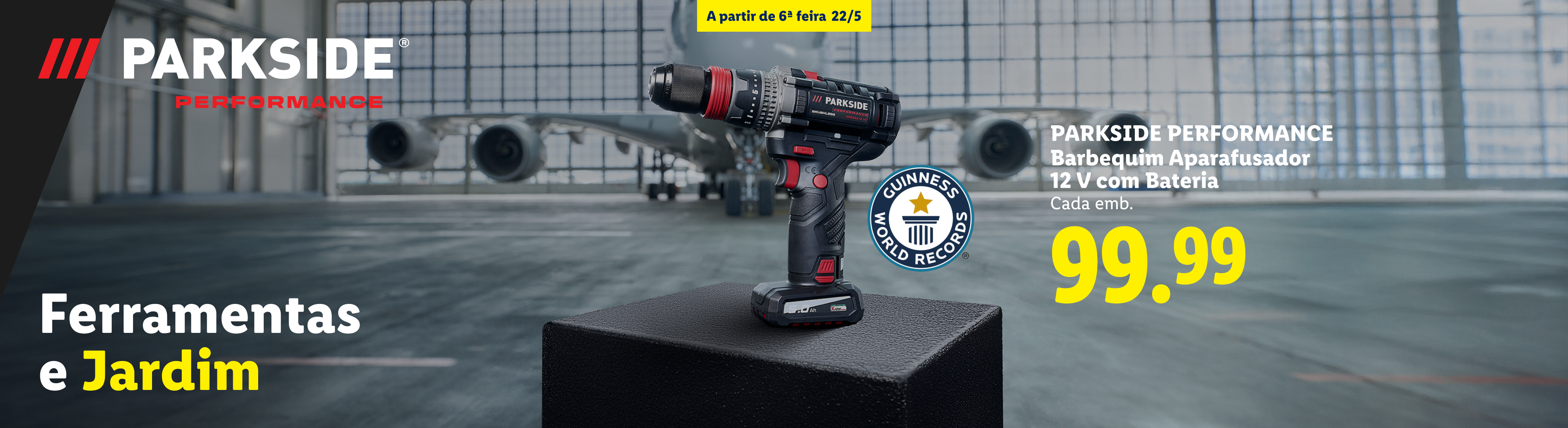 Berbequim aparafusador de 12V com bateria, com o selo Guinness World Records, em fundo de hangar.