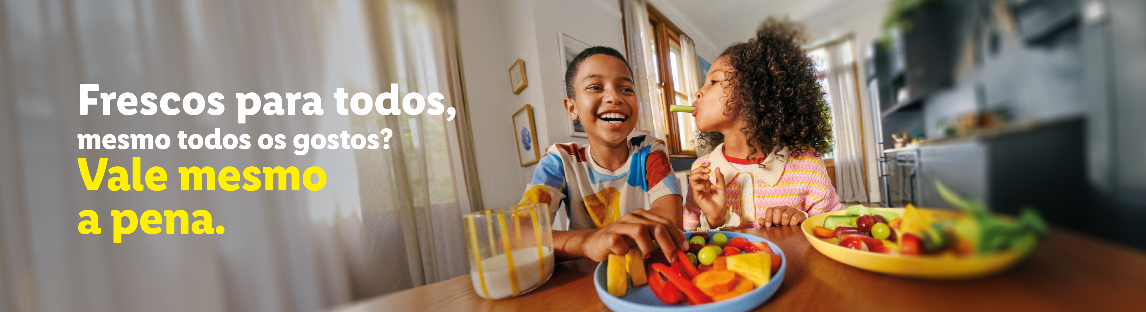 Duas crianças felizes a comer fruta e legumes frescos, com o texto 'Frescos para todos, mesmo todos os gostos? Vale mesmo a pena.'