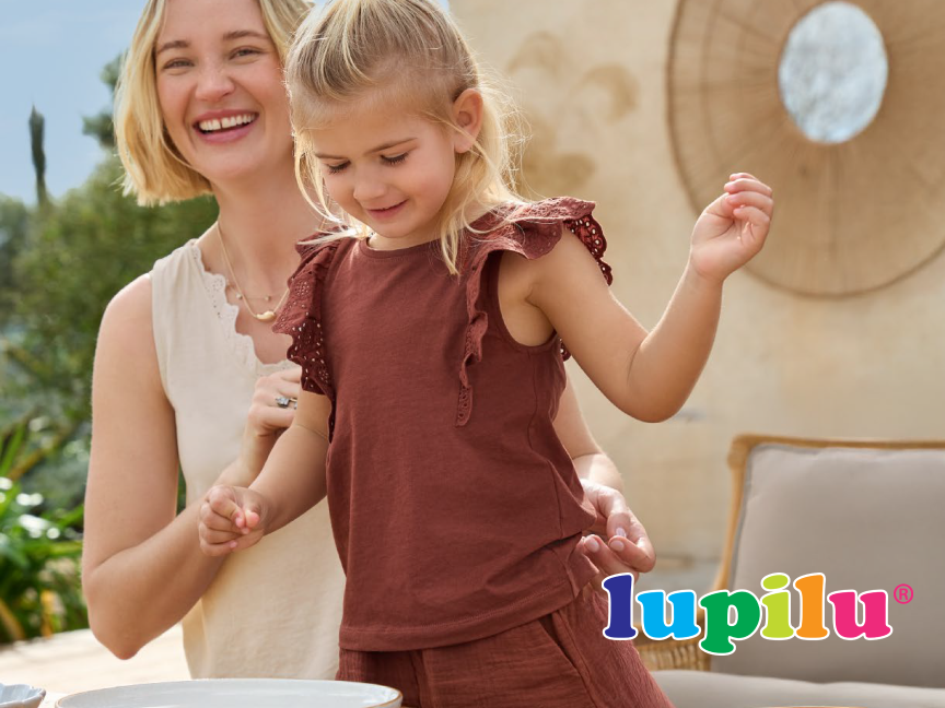 Mãe e filha usando roupas Lupilu, em um ambiente descontraído ao ar livre.