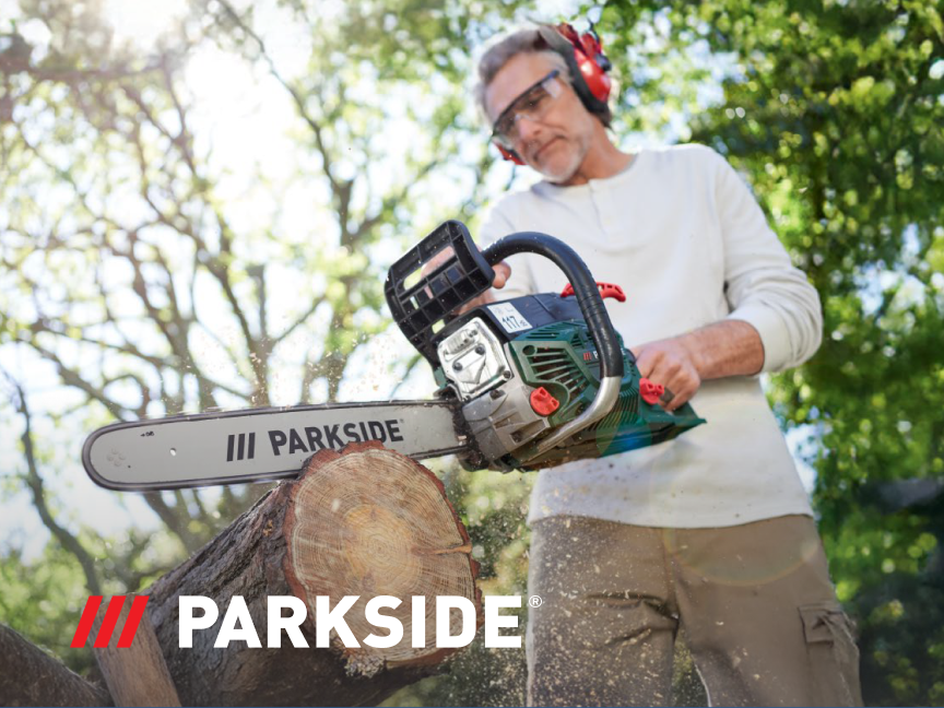 Um homem usa uma serra elétrica Parkside para cortar uma tora de madeira.