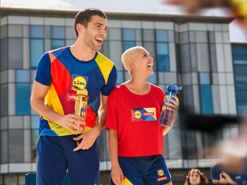 Dois atletas felizes usam roupas da Lidl Trek e seguram garrafas de água.