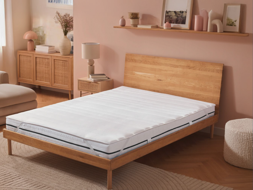 Um colchão de espuma viscoelástica branco em uma cama de madeira clara em um quarto estiloso.