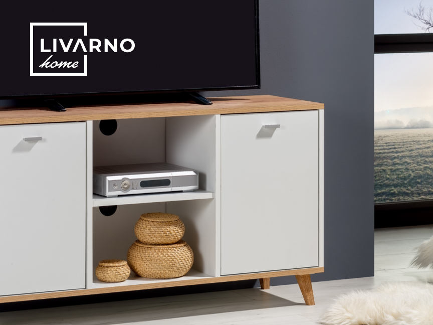 Um móvel de TV moderno com acabamento em madeira e branco, com um aparelho eletrônico e cestos de vime.