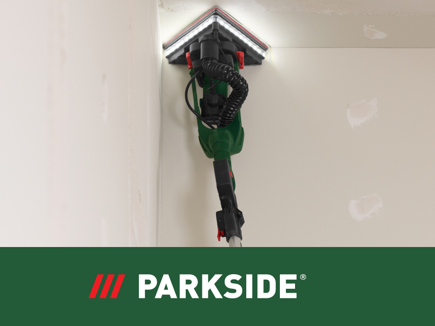 Uma lixadeira de parede Parkside em uso, lixando um canto de uma parede.