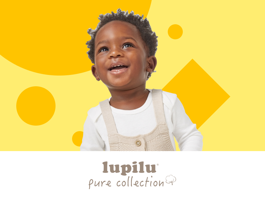 Bebê sorridente em macacão de malha, com o logotipo Lupilu Pure Collection.