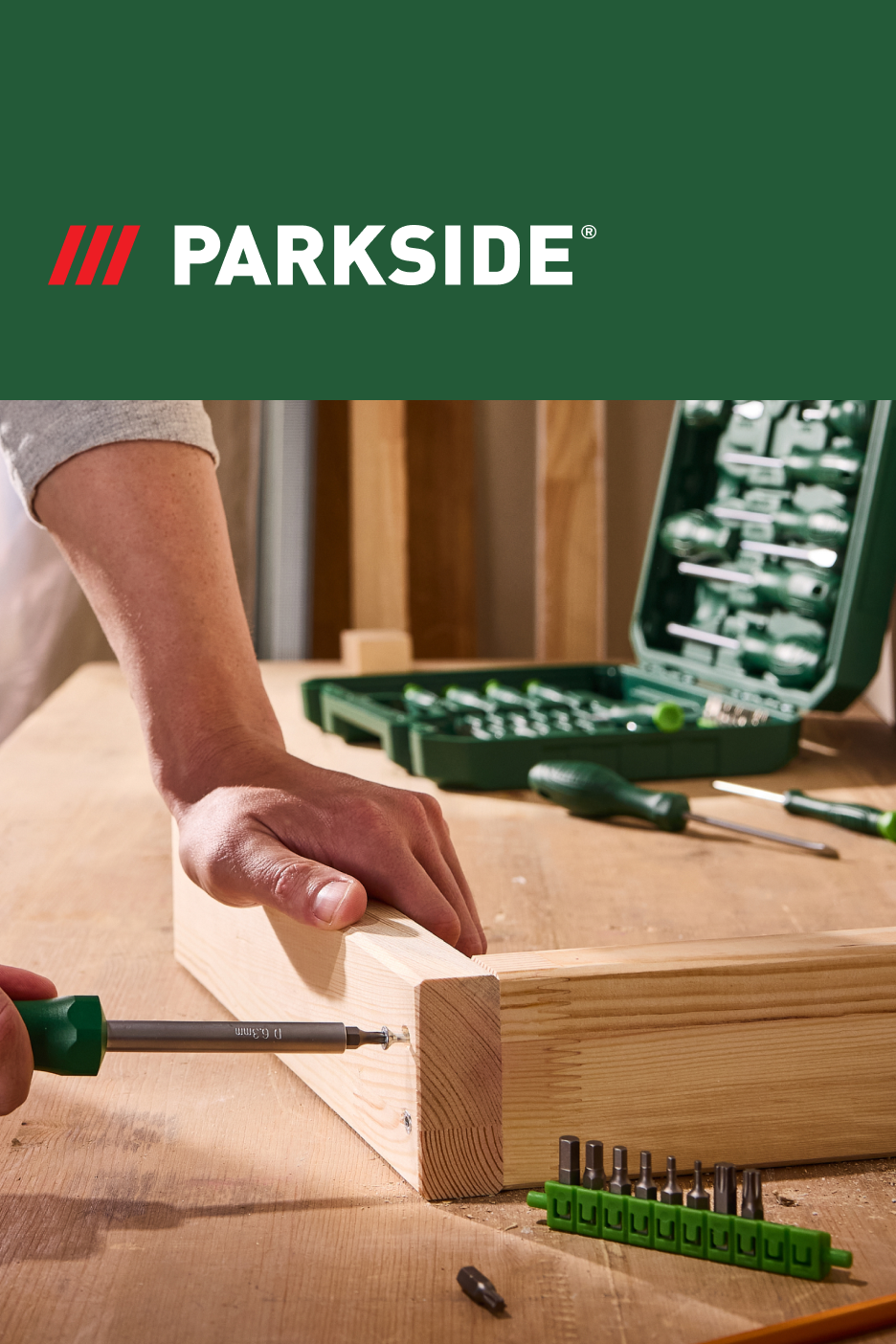 Um homem usando uma chave de fenda Parkside para montar peças de madeira, com um kit de ferramentas ao fundo.