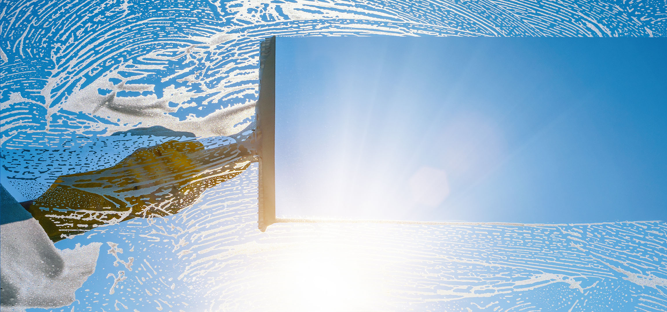 Limpeza de janelas com espuma de sabão num céu azul.